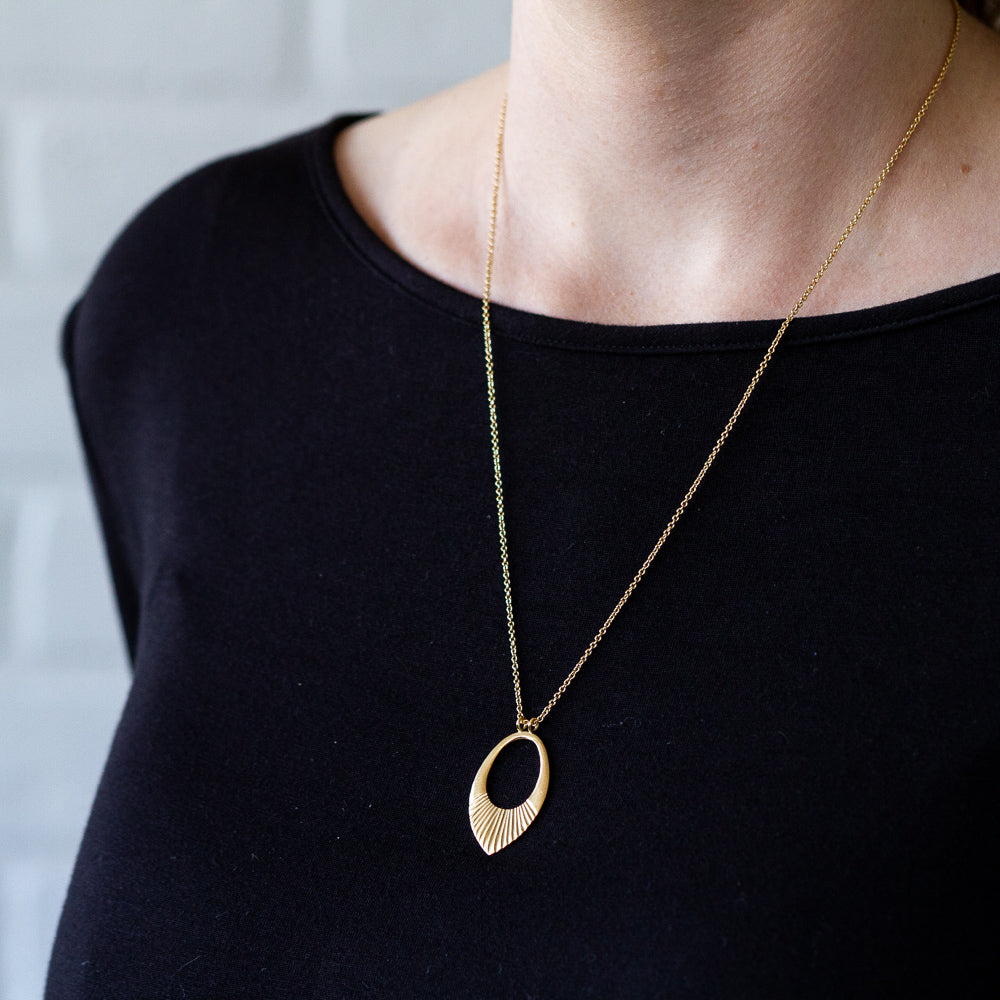 Gold vermeil medium open petal shape pendant with a textured bottom on a 22" vermeil chain around a neck