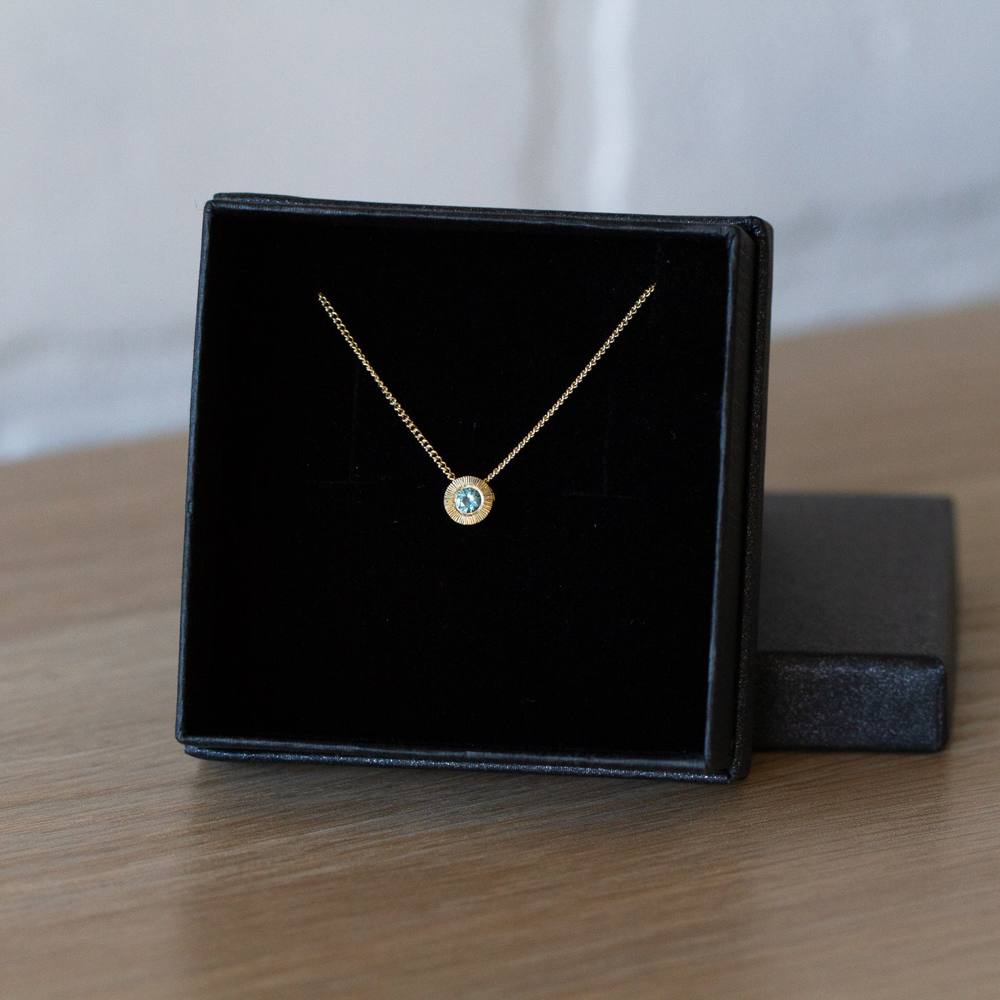 14k yellow gold small aurora necklace with a teal Montana sapphire center in a gift box