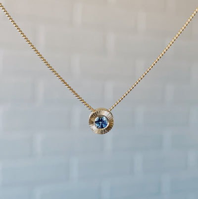 14k yellow gold small aurora necklace with a denim blue Montana sapphire center in natural light