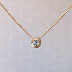 March birthstone 14k yellow gold Aurora necklace with aquamarine center and engraved sunburst halo border.