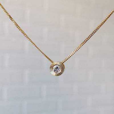 April birthstone 14k yellow gold Aurora necklace with diamond center and engraved sunburst halo border.