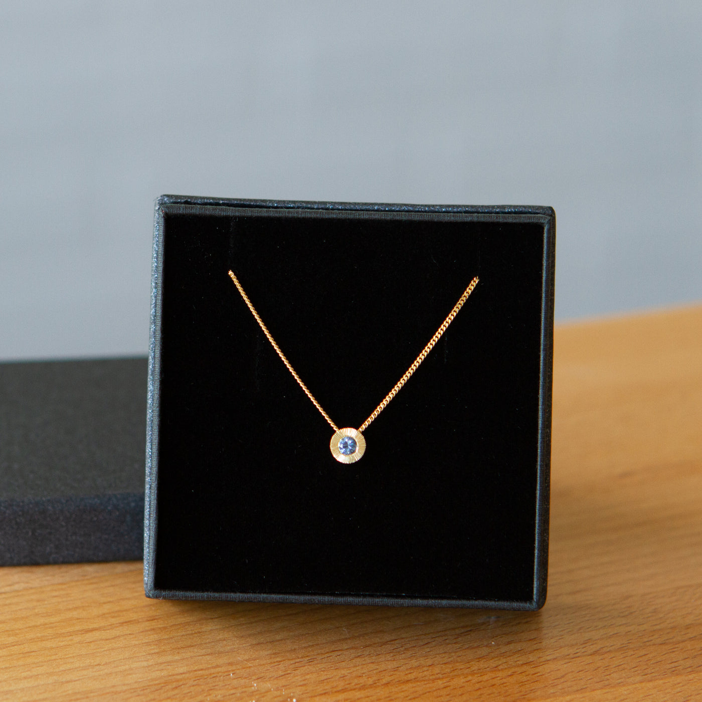 14k yellow gold small aurora necklace with a blue montana sapphire center in a gift box