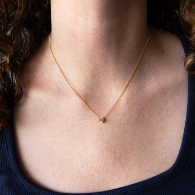 14k yellow gold small Aurora necklace with pink Montana sapphire center around a neck