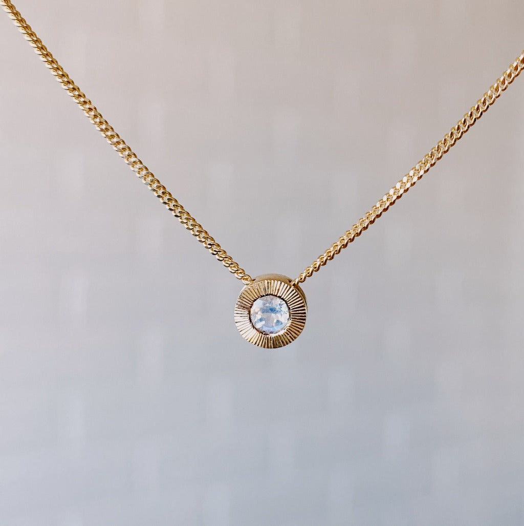June birthstone 14k yellow gold Aurora necklace with moonstone center and engraved sunburst halo border.