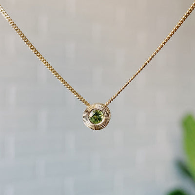 August birthstone 14k yellow gold Aurora necklace with peridot center and engraved sunburst halo border.