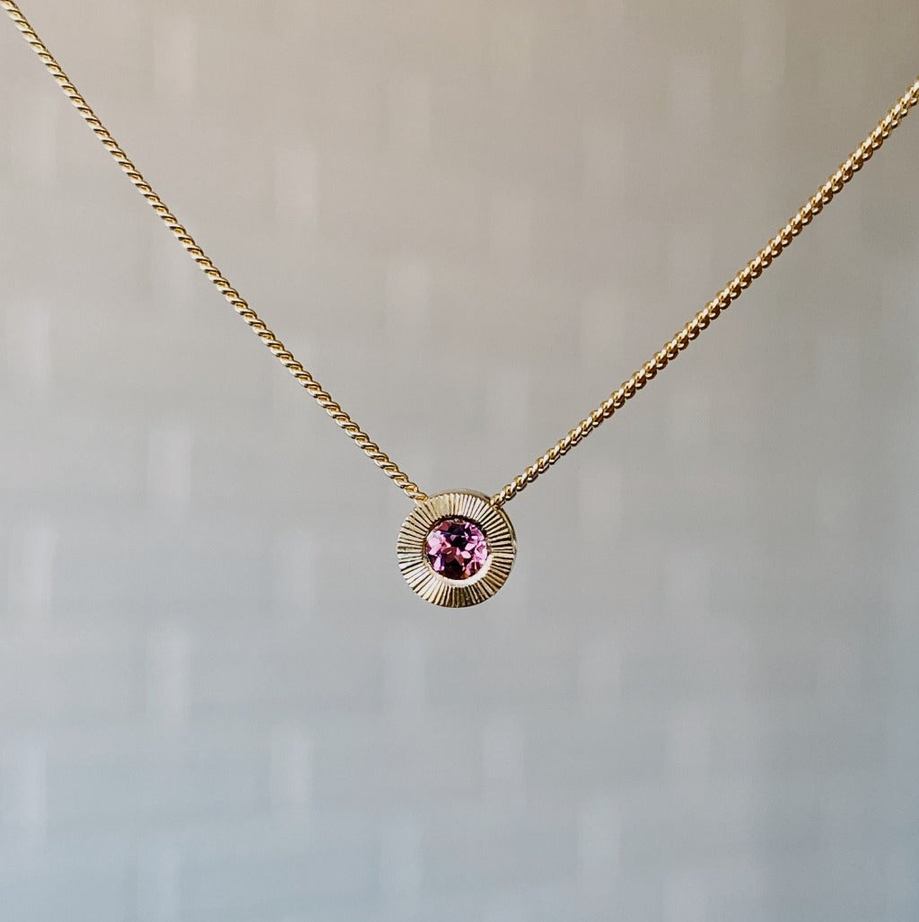 October birthstone 14k yellow gold Aurora necklace with pink tourmaline center and engraved sunburst halo border.