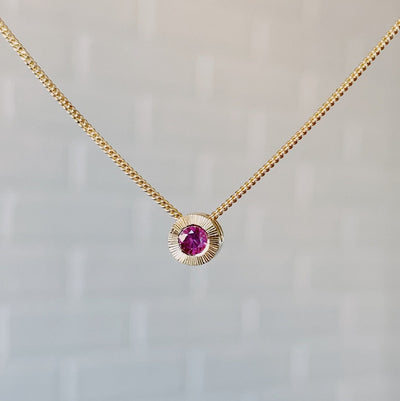 July birthstone 14k yellow gold Aurora necklace with ruby center and engraved sunburst halo border.