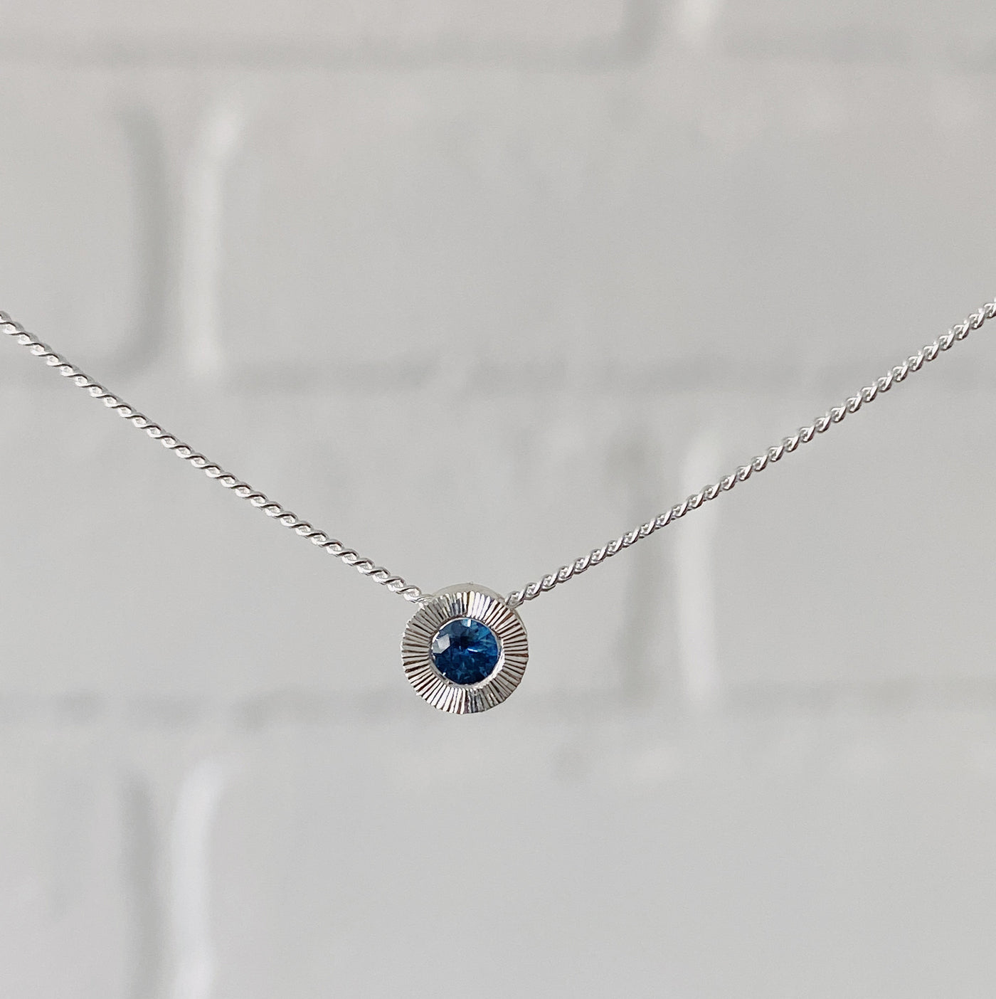 Sterling silver small aurora necklace with a blue Montana sapphire center  in natural light