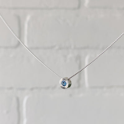 Side view sterling silver small aurora necklace with a blue Montana sapphire center in natural light
