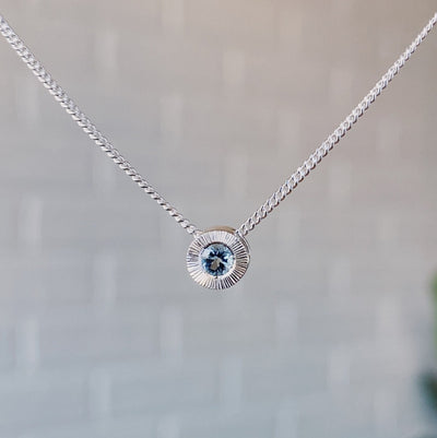March birthstone sterling silver Aurora necklace with aquamarine center and engraved sunburst halo border.