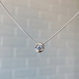 April birthstone sterling silver Aurora necklace with diamond center and engraved sunburst halo border.