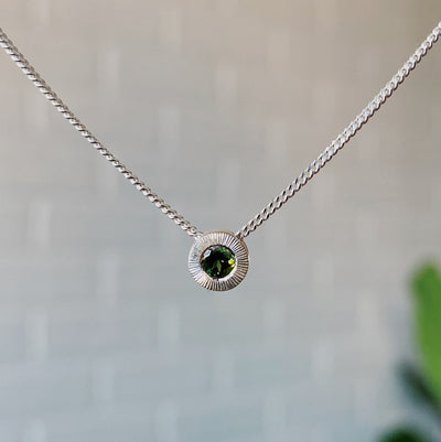 October birthstone sterling silver Aurora necklace with green tourmaline center and engraved sunburst halo border.
