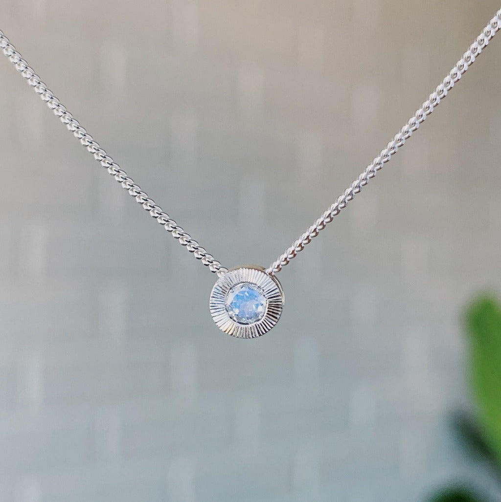 June birthstone sterling silver Aurora necklace with moonstone center and engraved sunburst halo border.