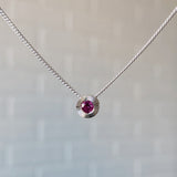 July birthstone sterling silver Aurora necklace with ruby center and engraved sunburst halo border.