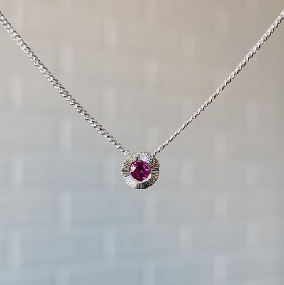 July birthstone sterling silver Aurora necklace with ruby center and engraved sunburst halo border.