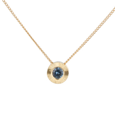 14k yellow gold Medium aurora necklace with a denim blue Montana sapphire center and engraved halo border on a white background