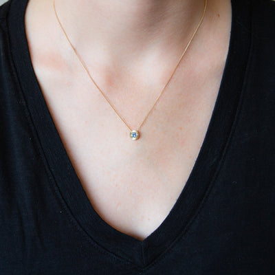 14k yellow gold Medium aurora necklace with a denim blue Montana sapphire center and engraved halo border around a neck