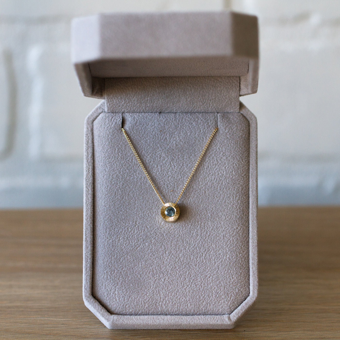14k yellow gold Medium aurora necklace with a denim blue Montana sapphire center and engraved halo border in a gift box