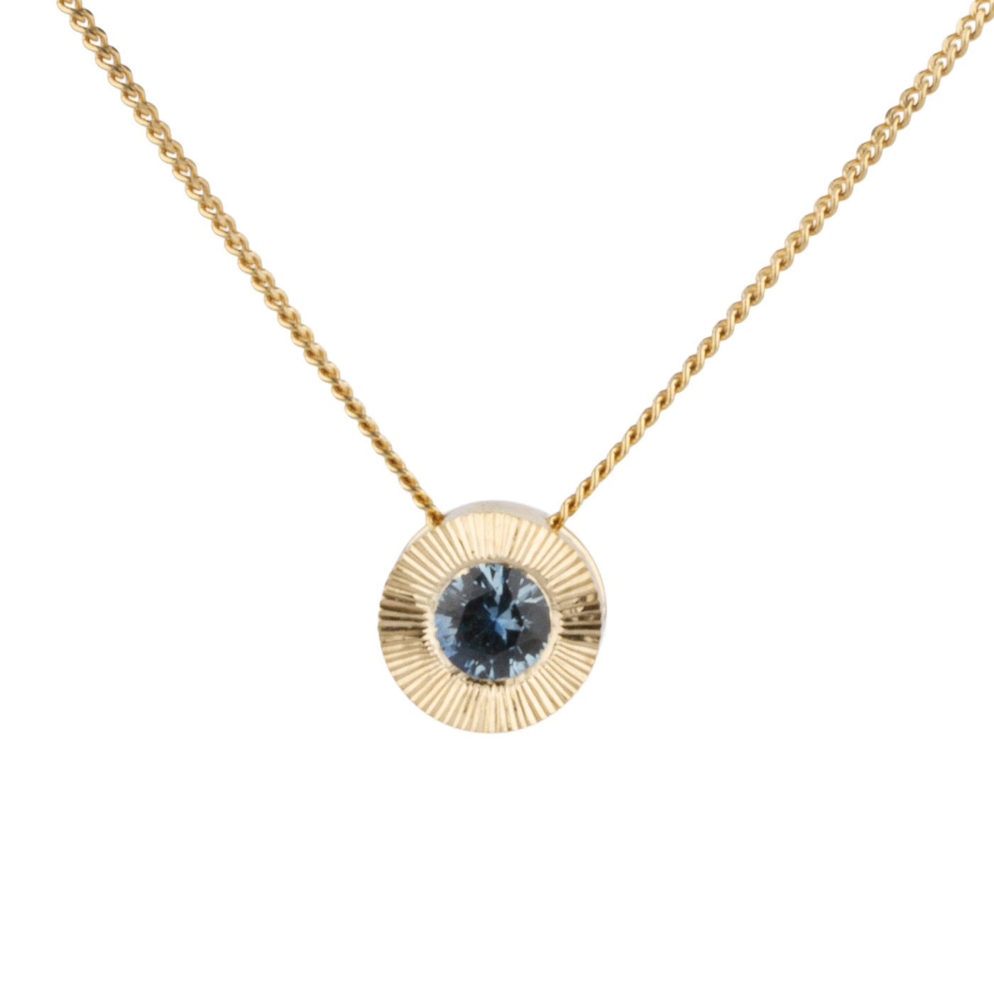 14k yellow gold large aurora necklace with a denim blue Montana sapphire center and engraved halo border on a white background