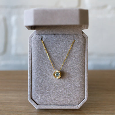 14k yellow gold large aurora necklace with a denim blue Montana sapphire center and engraved halo border in a gift box