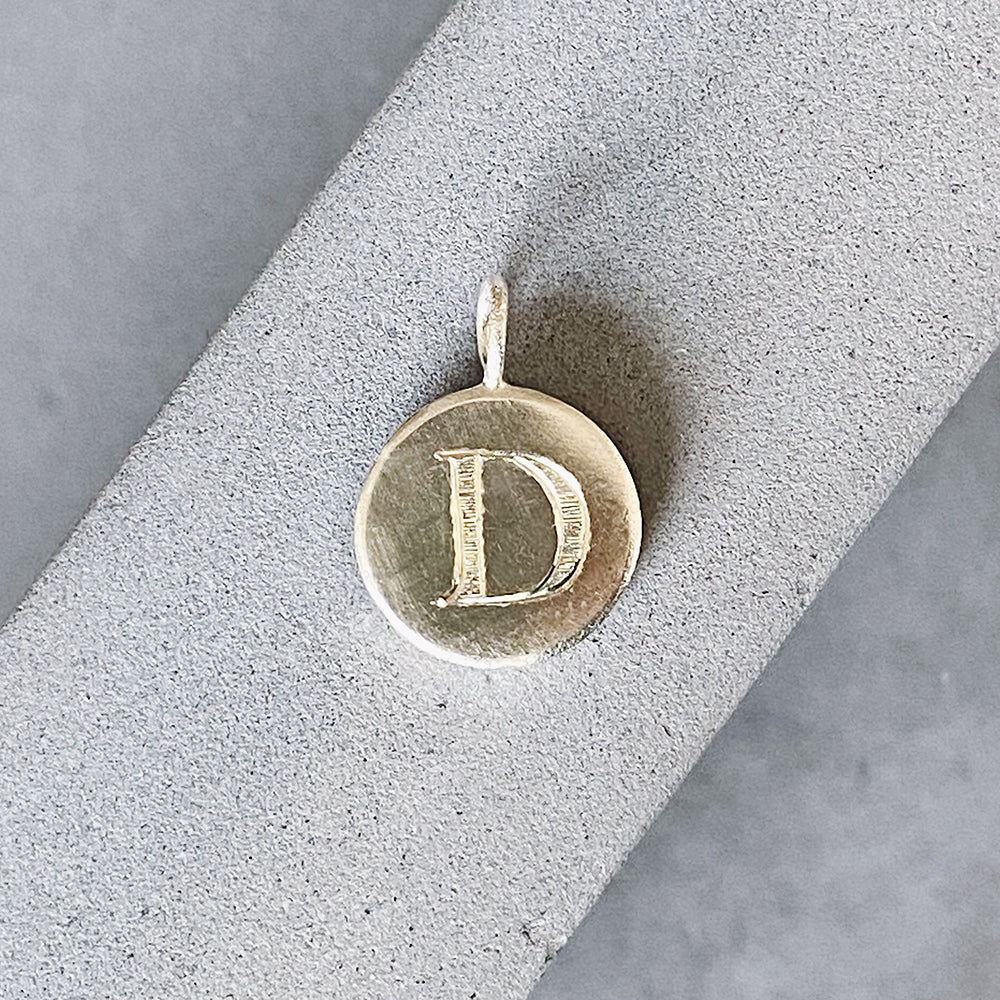 Sterling silver round pendant with an engraved block letter D