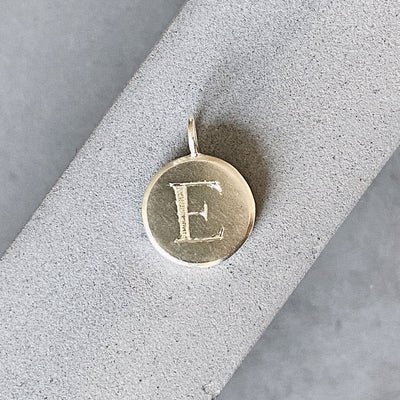 Sterling silver round pendant with an engraved block letter E