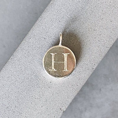 Sterling silver round pendant with an engraved block letter H
