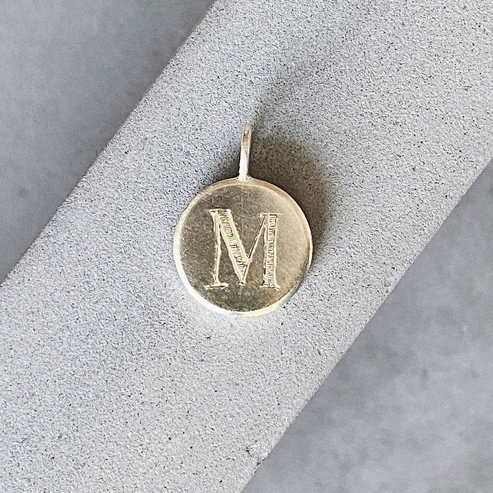 Sterling silver round pendant with an engraved block letter M