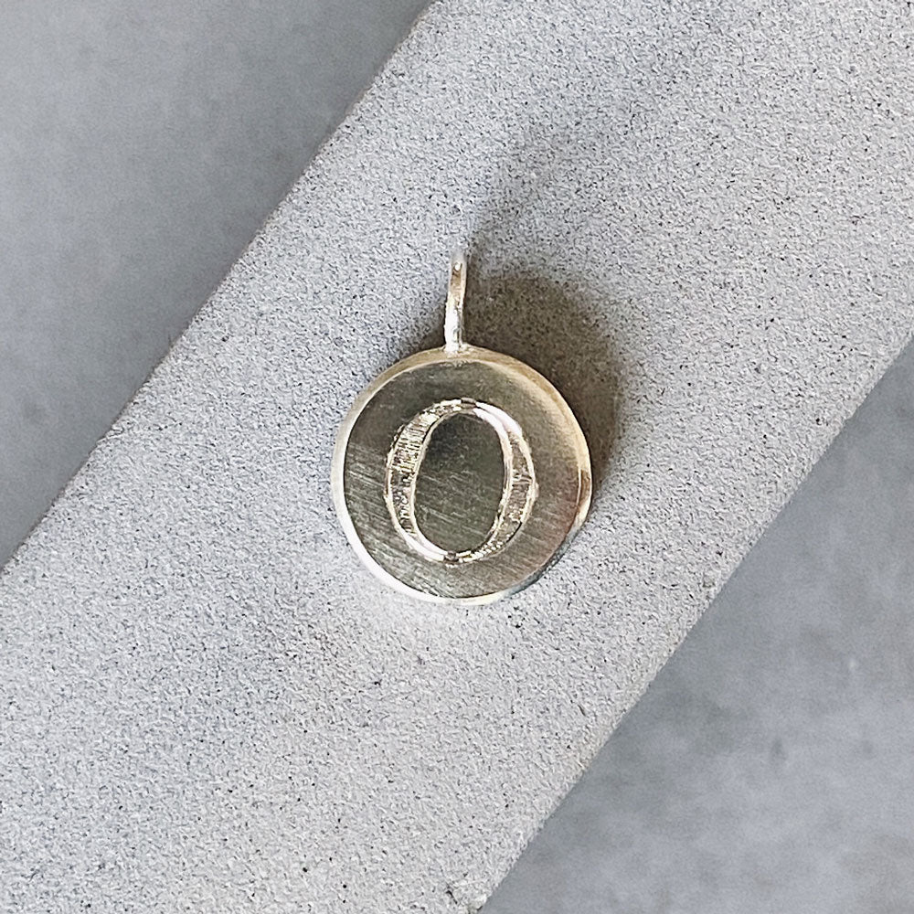 Sterling silver round pendant with an engraved block letter O