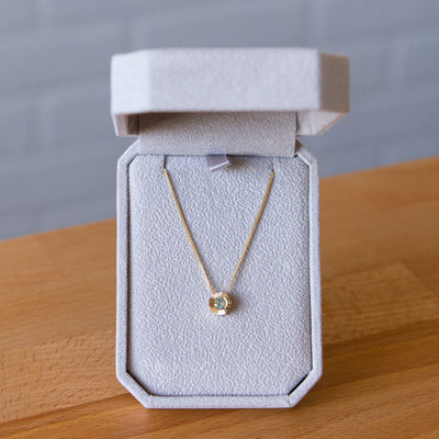 14k yellow gold Medium aurora necklace with a light teal Montana sapphire center in a gift box