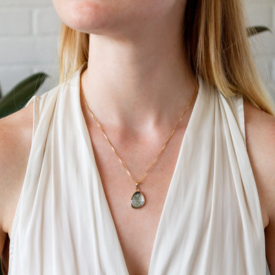 A model wears the moss aquamarine silver and gold bijou pendant on a gold box chain