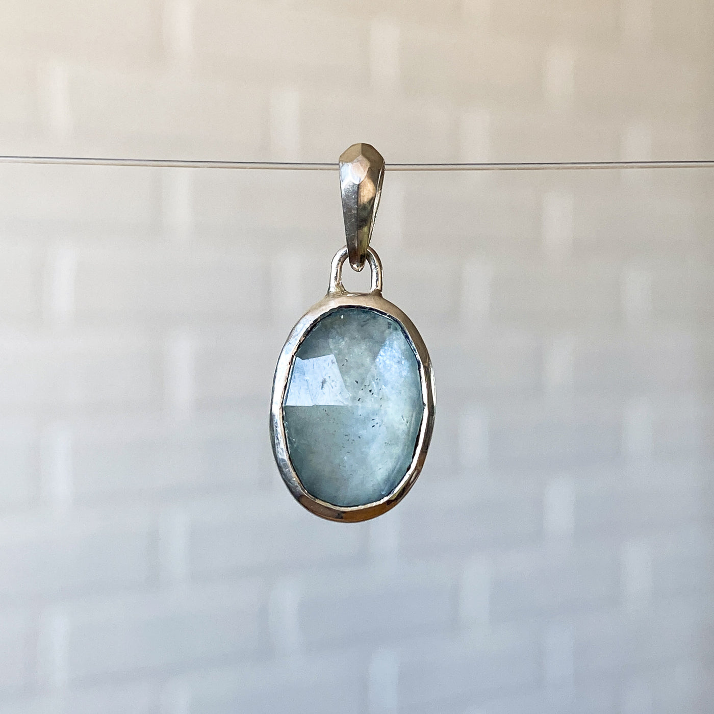 Oval Rose cut cloudy aquamarine in a sterling silver bezel pendant with a faceted silver bail.