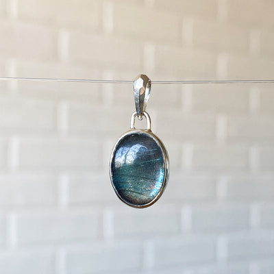 Smooth Oval Labradorite cabochon in a sterling silver bezel with a faceted bail