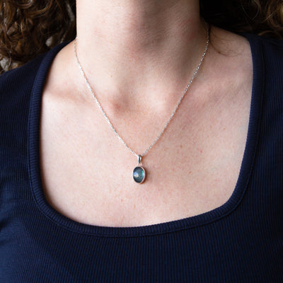 Smooth Oval Labradorite cabochon in a sterling silver bezel with a faceted bail around a neck