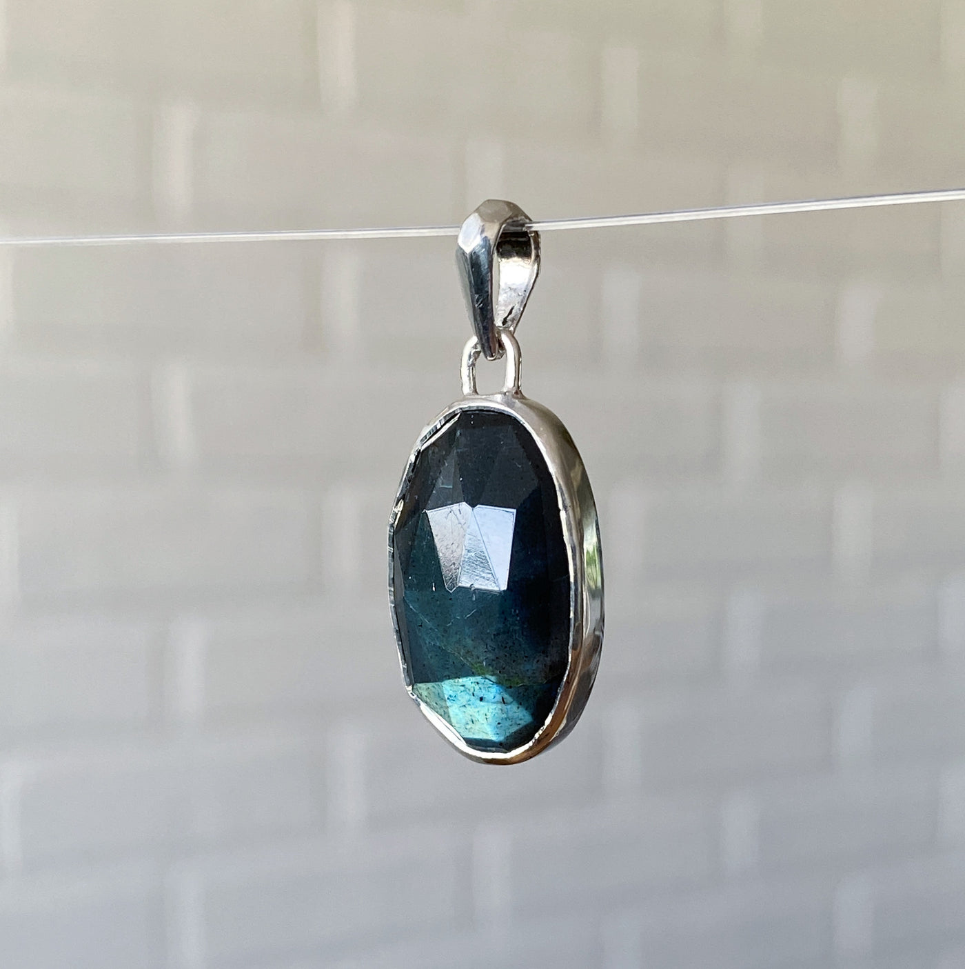 Side view of Large oval rose cut labradorite pendant crafted from sterling silver with a faceted silver bail