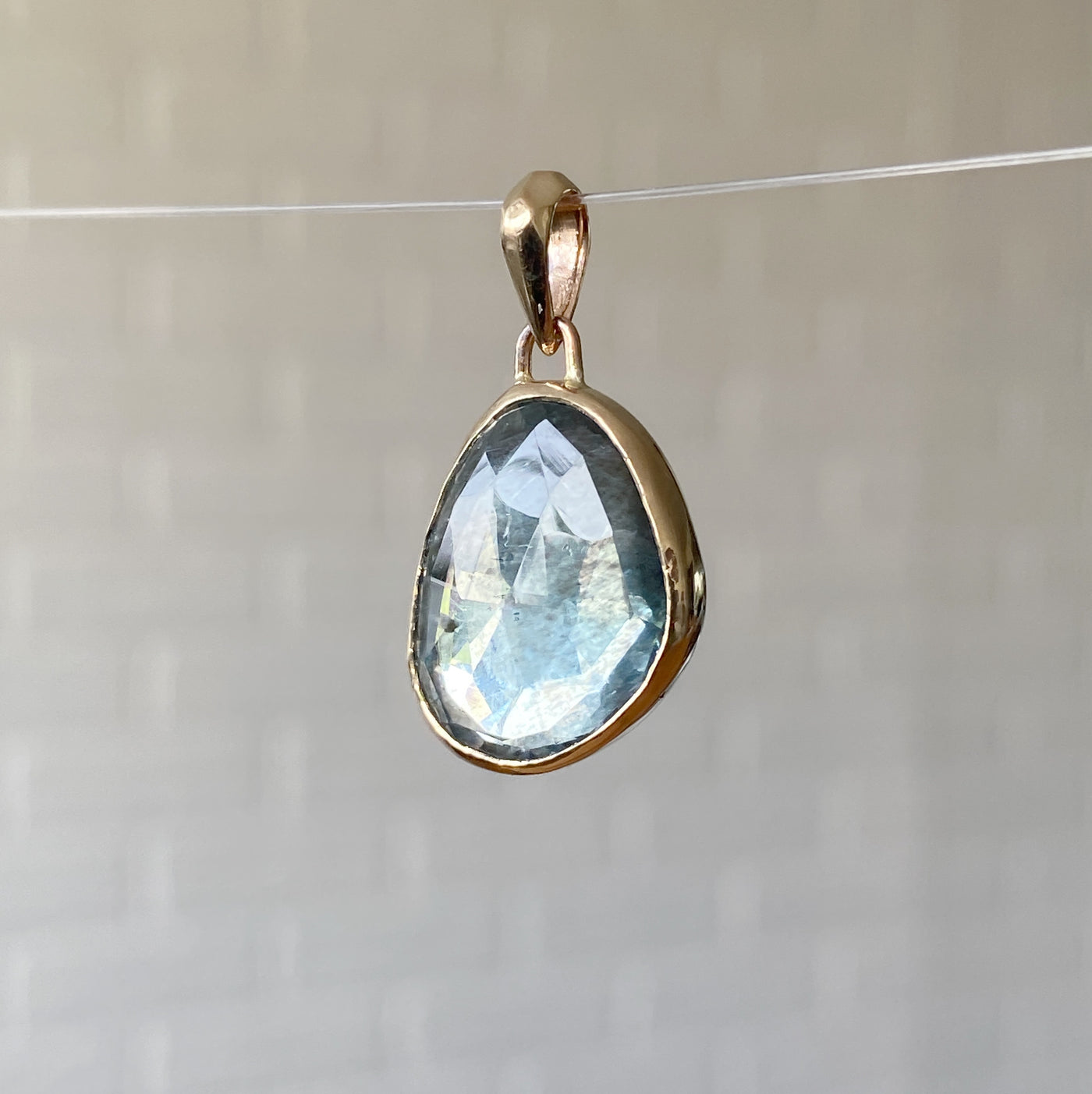 Side view of rose cut moss aquamarine bijou pendant with a gold bezel and faceted gold bail