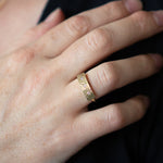 Yellow gold bar ring with three diamonds and a carved sunburst design around each by Corey Egan on a hand