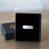 Sterling silver bar ring with three diamonds and a carved sunburst design around each by Corey Egan in a ring box