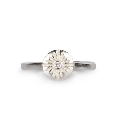 Small carved sunburst ring with a diamond center in sterling silver on a white background by Corey Egan
