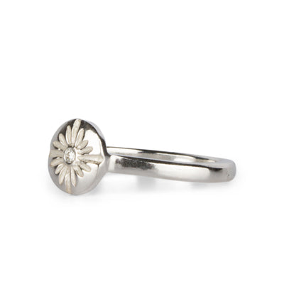 Small carved sunburst ring with a diamond center in sterling silver side view on a white background by Corey Egan