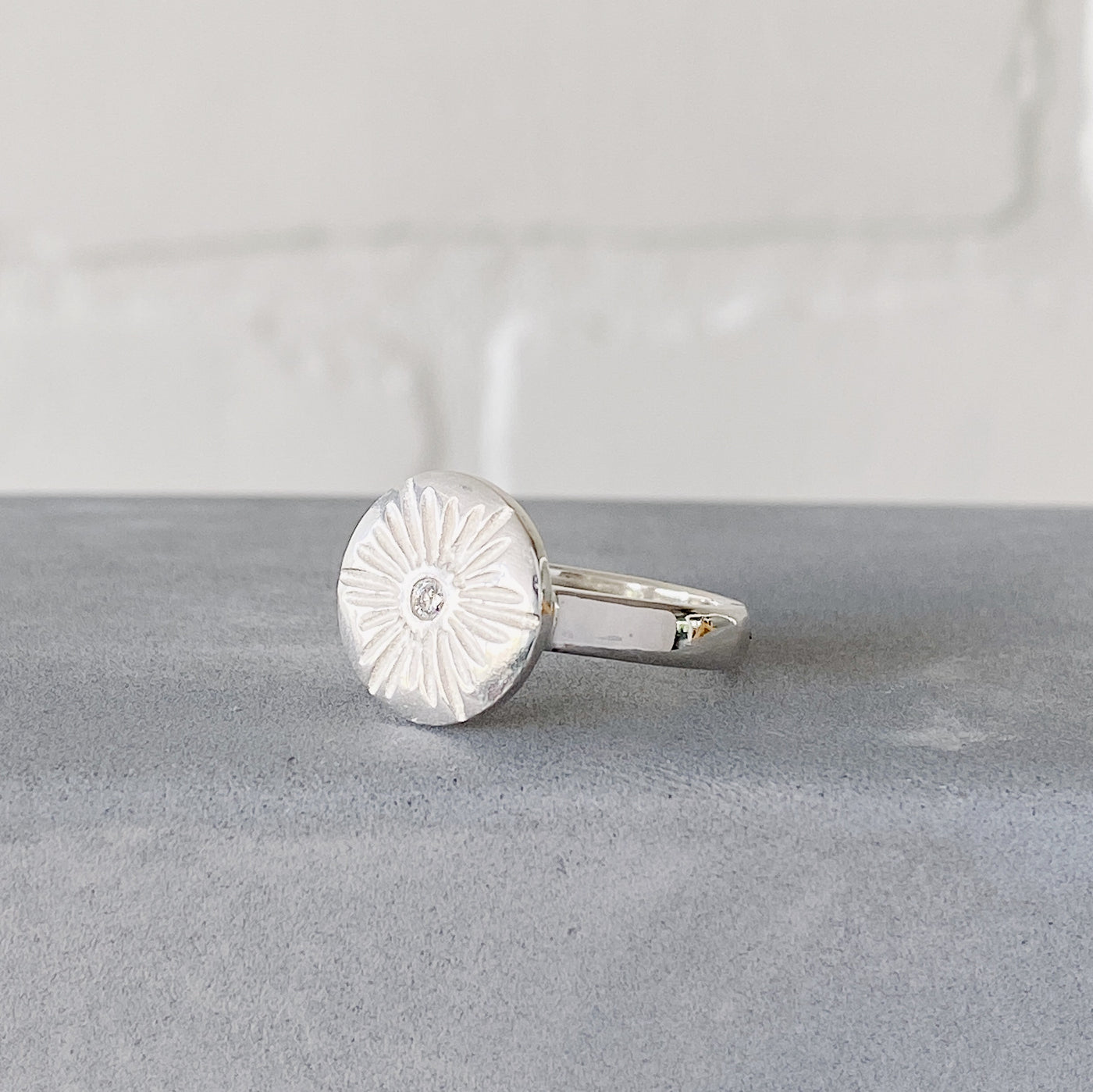 Large carved sunburst ring with a diamond center in sterling silver side view by Corey Egan