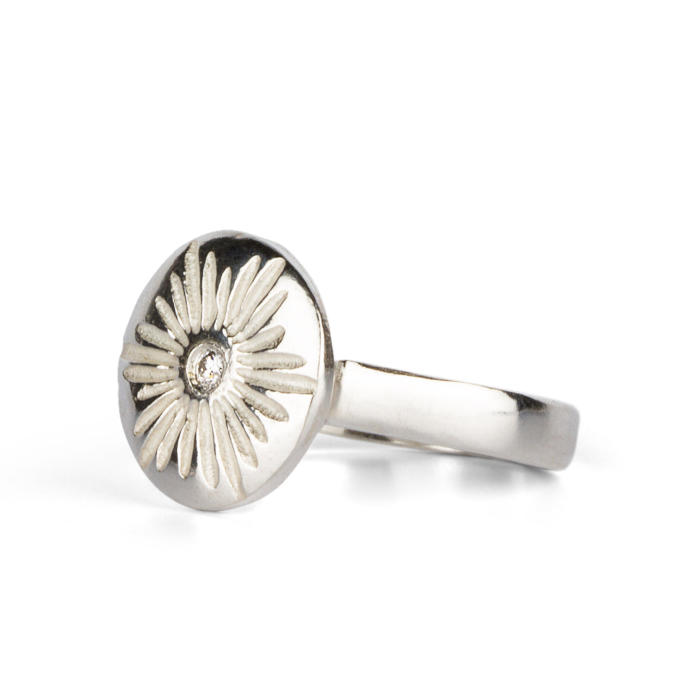 Large carved sunburst ring with a diamond center in sterling silver side view on a white background by Corey Egan