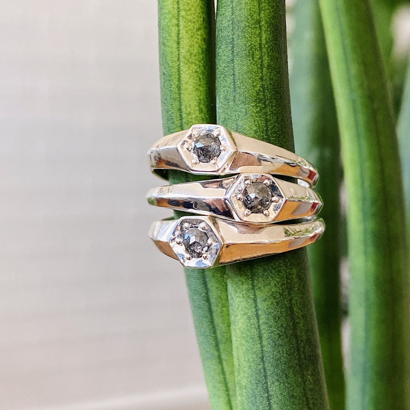 A stack of Sterling silver signet rings with bead set rose cut salt and pepper diamonds