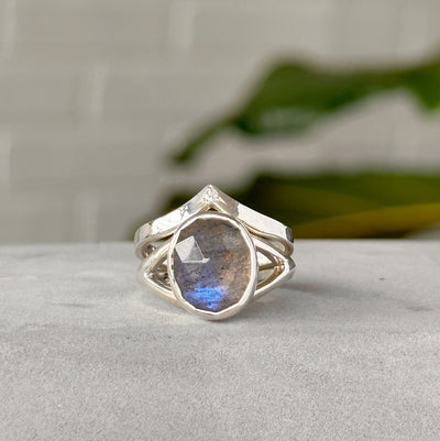 Silver peaked band with single star set diamond styled with a labradorite ring in front of a white wall
