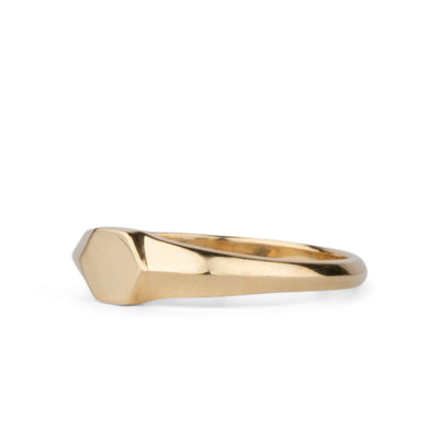 Gold low profile signet ring with a hexagon face side view on a white background