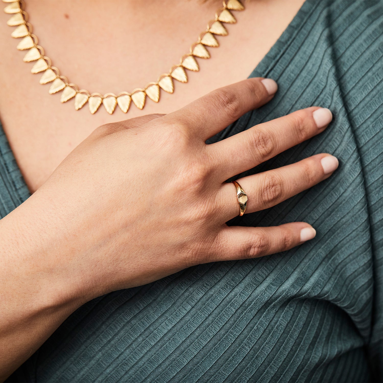 Gold low profile signet ring with a hexagon face on a hand