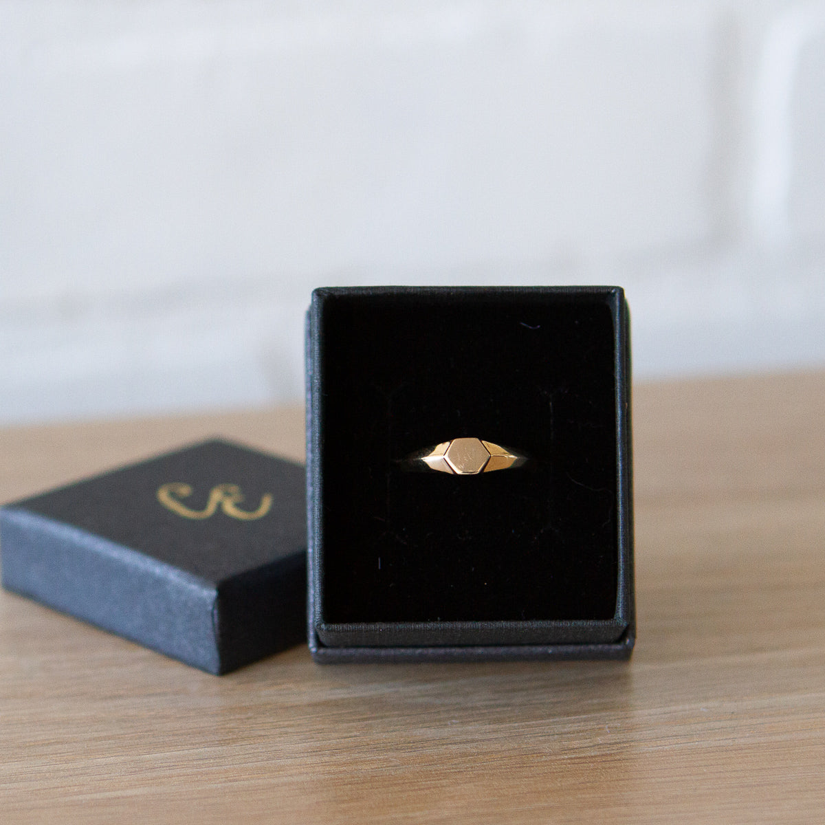 Gold low profile signet ring with a hexagon face in a gift box