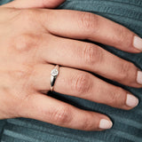 Low profile sterling silver signet ring with a hexagon shaped face and a white center diamond on a hand