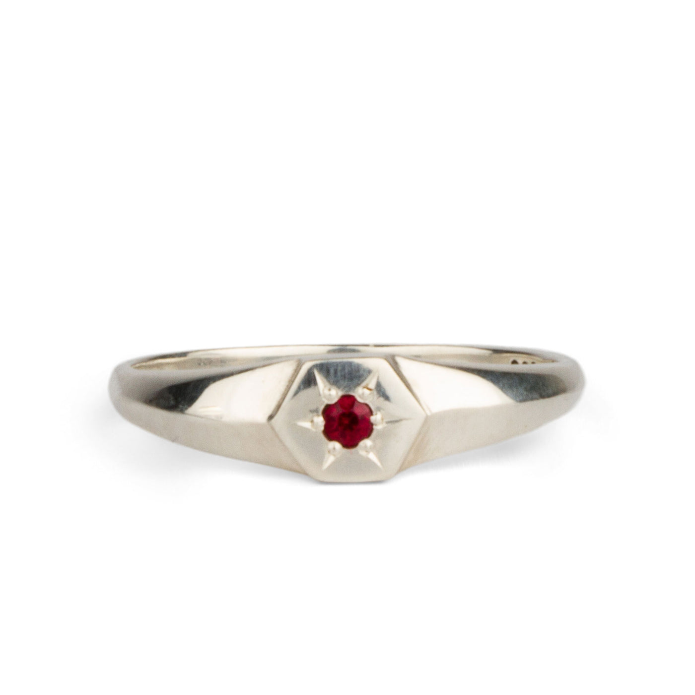 sterling silver signet ring with a star set ruby in the center on a white background