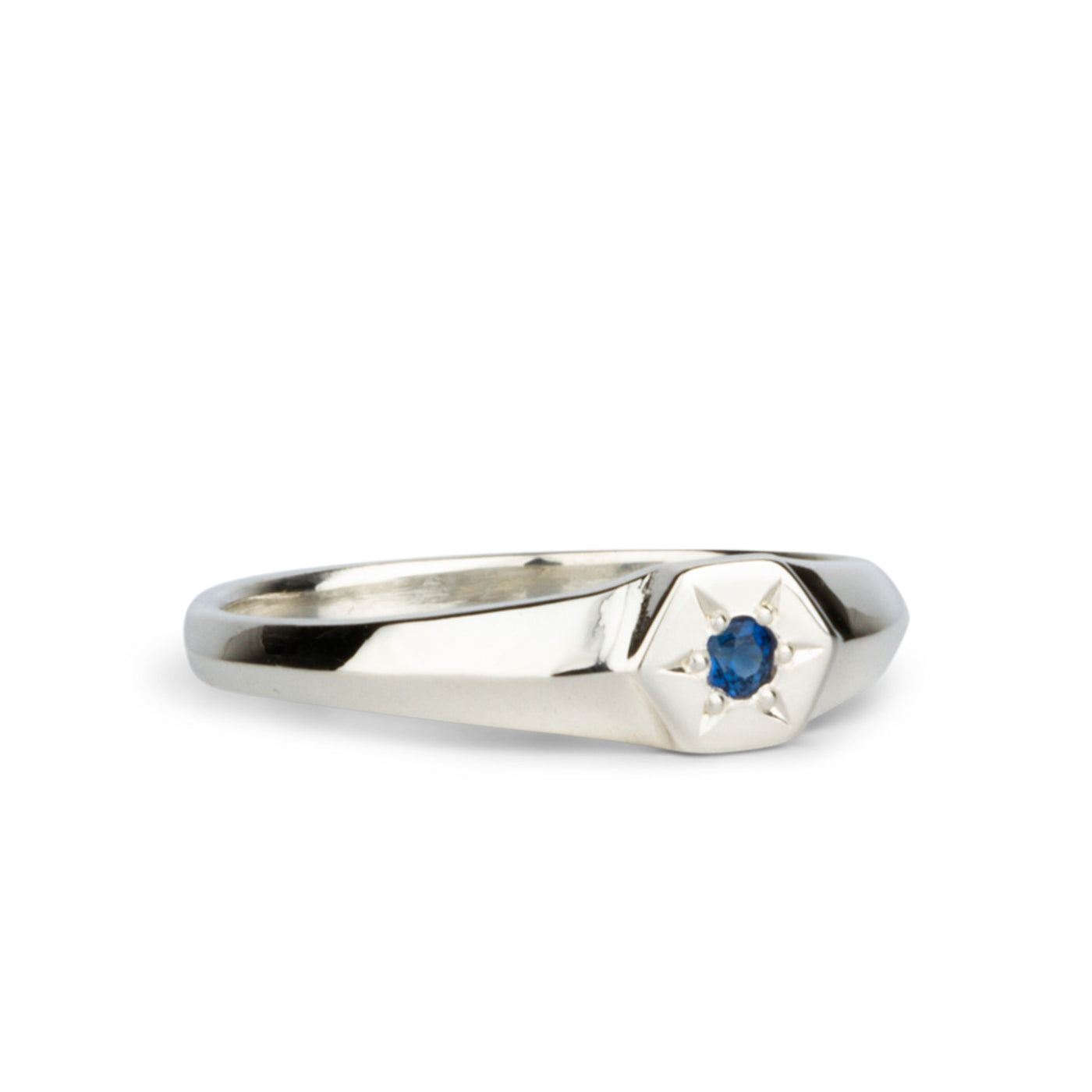 Side view of hexagon silver signet ring with a star set sapphire center on a white background
